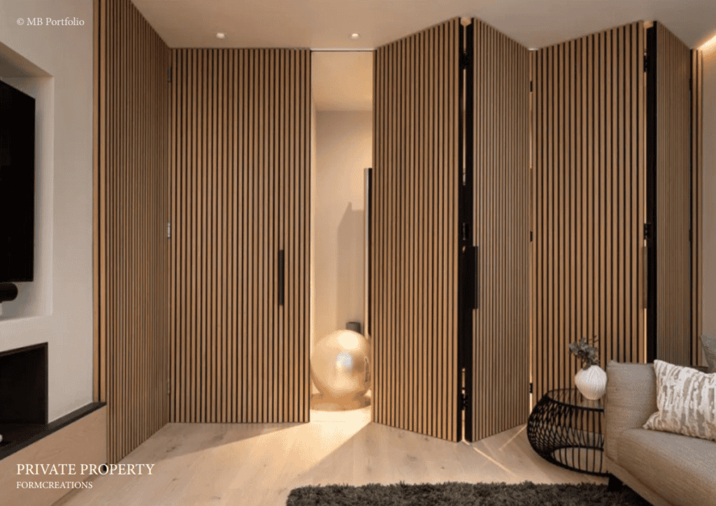 A modern living room featuring floor-to-ceiling wood slatted panels with one curved panel opened to reveal another space. ambient lighting enhances the warm tones, with minimal furnishings including a sofa and a decorative ball light.