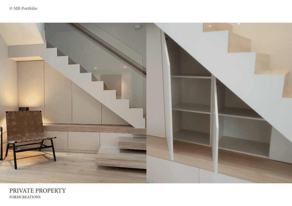 A minimalist interior featuring a white staircase alongside a wooden bench under it, with a geometrically structured white shelving unit on the right, emphasizing modern architectural design.